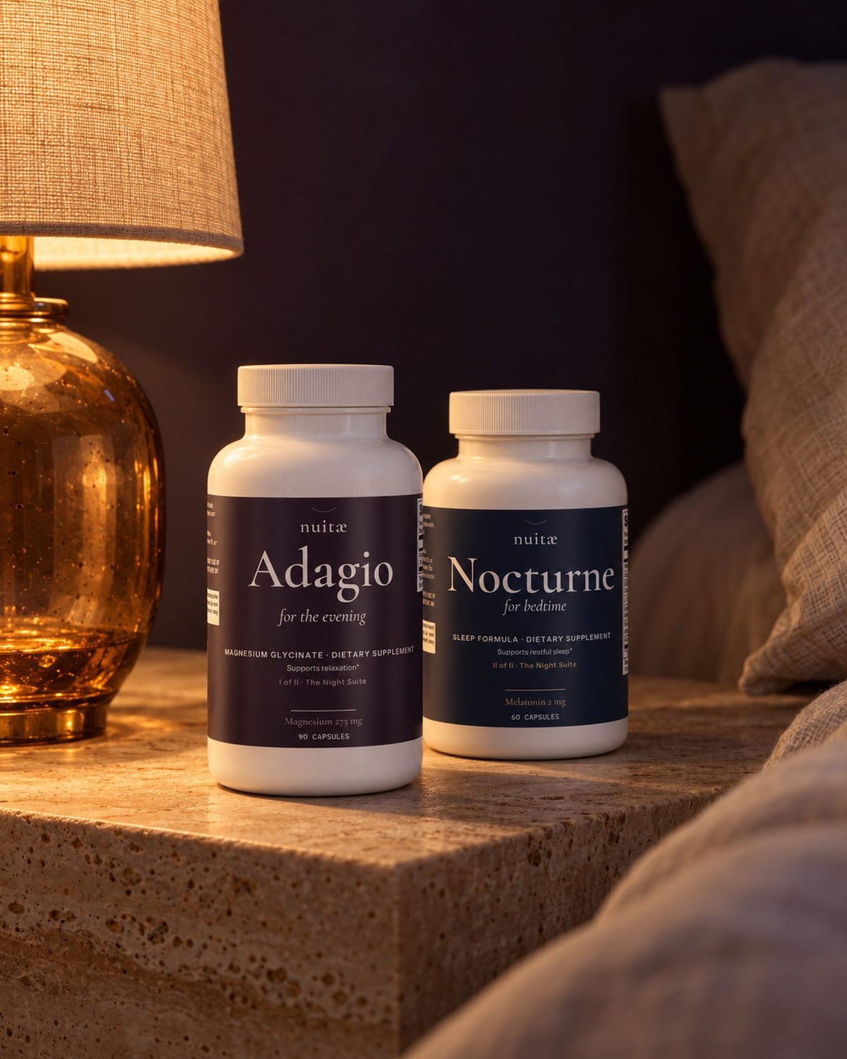 Adagio and Nocturne bottles on a travertine ledge beside a lit table lamp at night